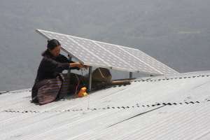A woman installs a solar panels on the roof of her house in rural Bhutan